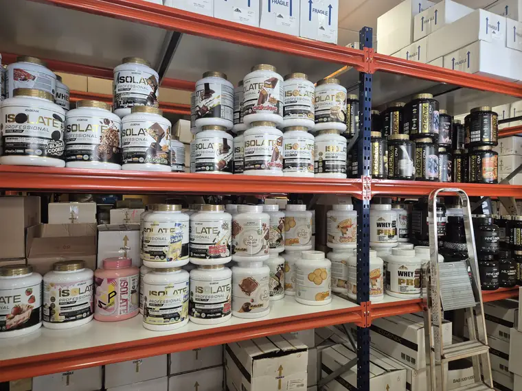 Almacén de la tienda con estanterías cargadas de botes de proteína