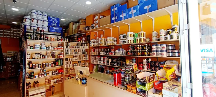 Interior de Protein Center hoy, con el mostrador y las estanterías llenas